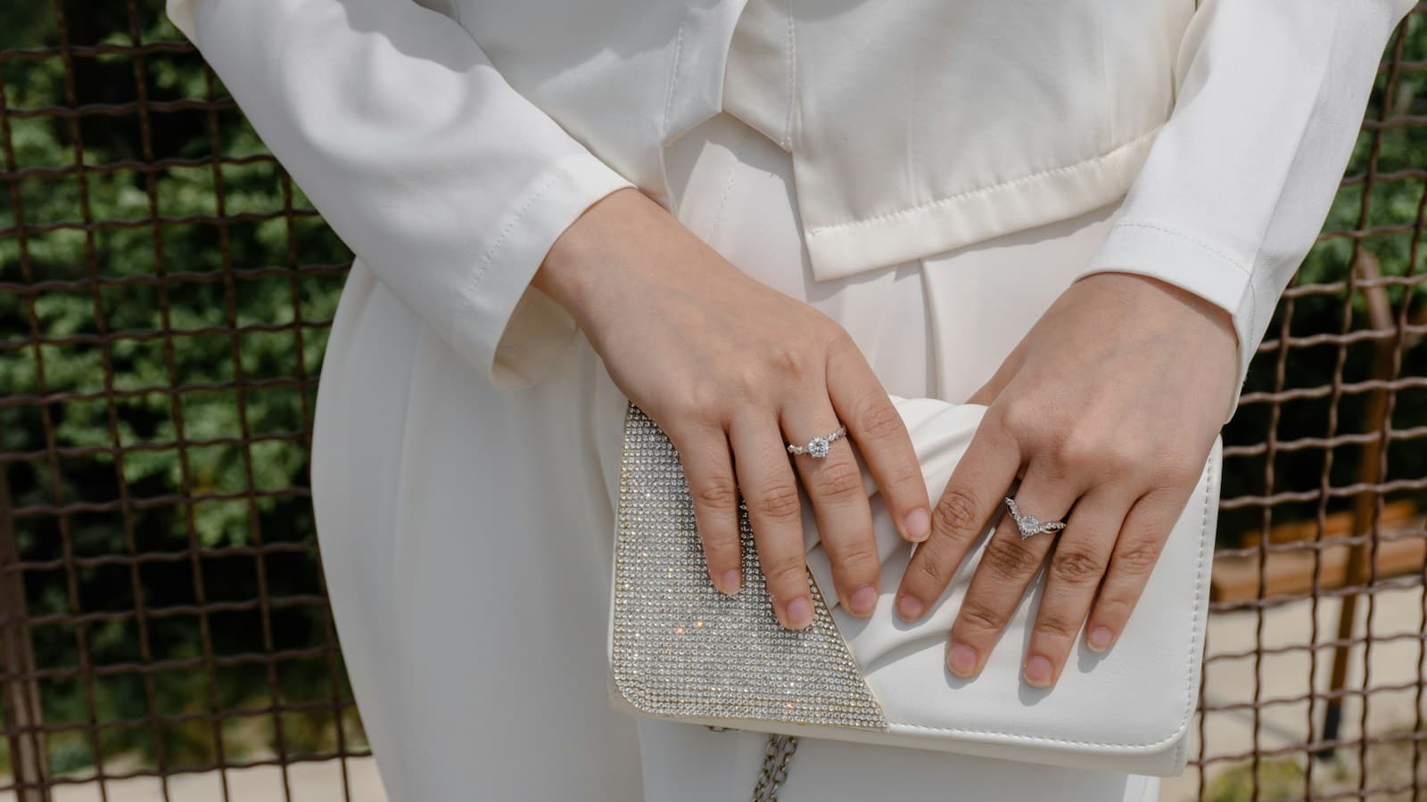 Hands holding a white beaded clutch bag with rings