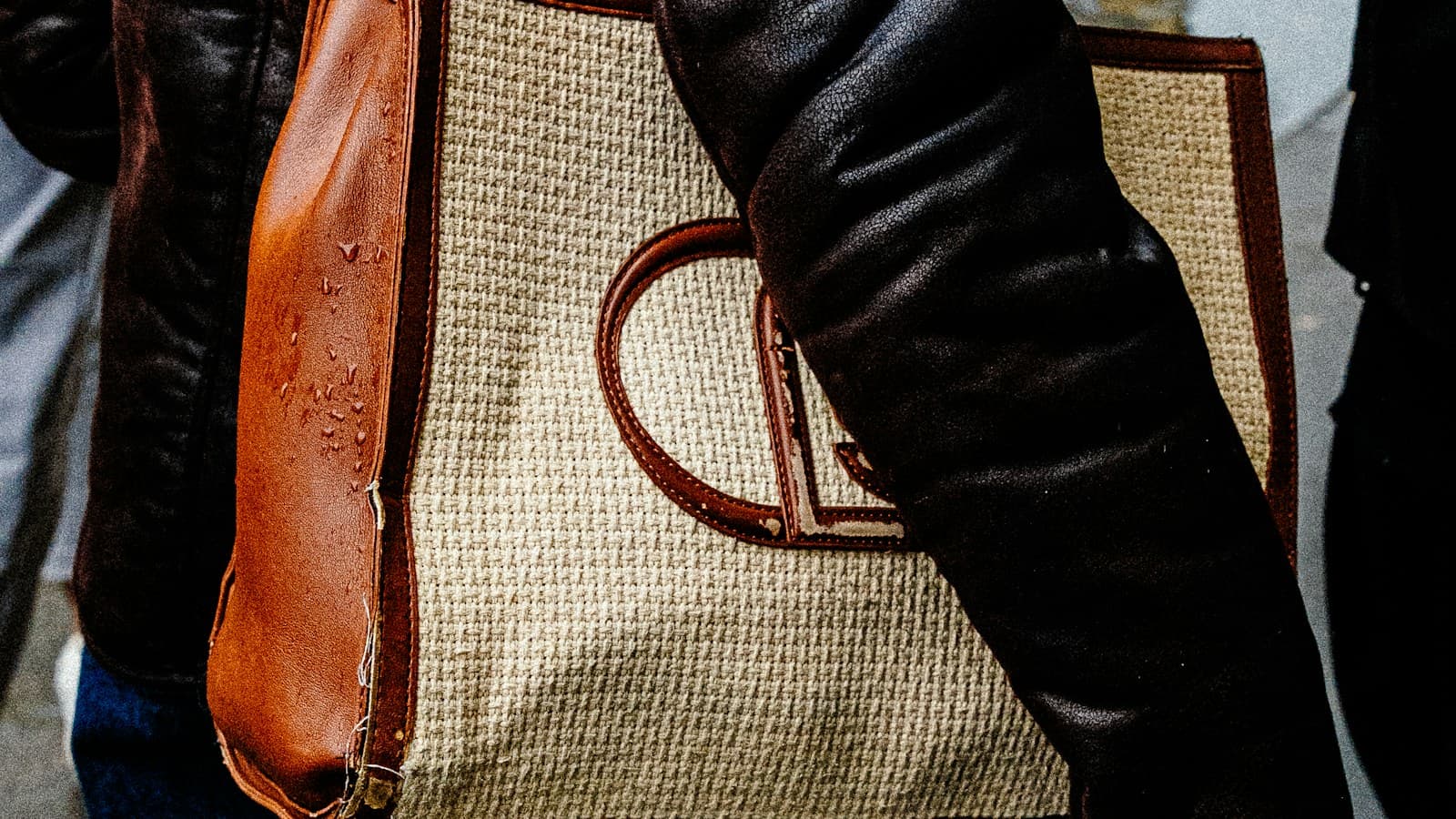 Woman in a leather jacket carries a tote bag
