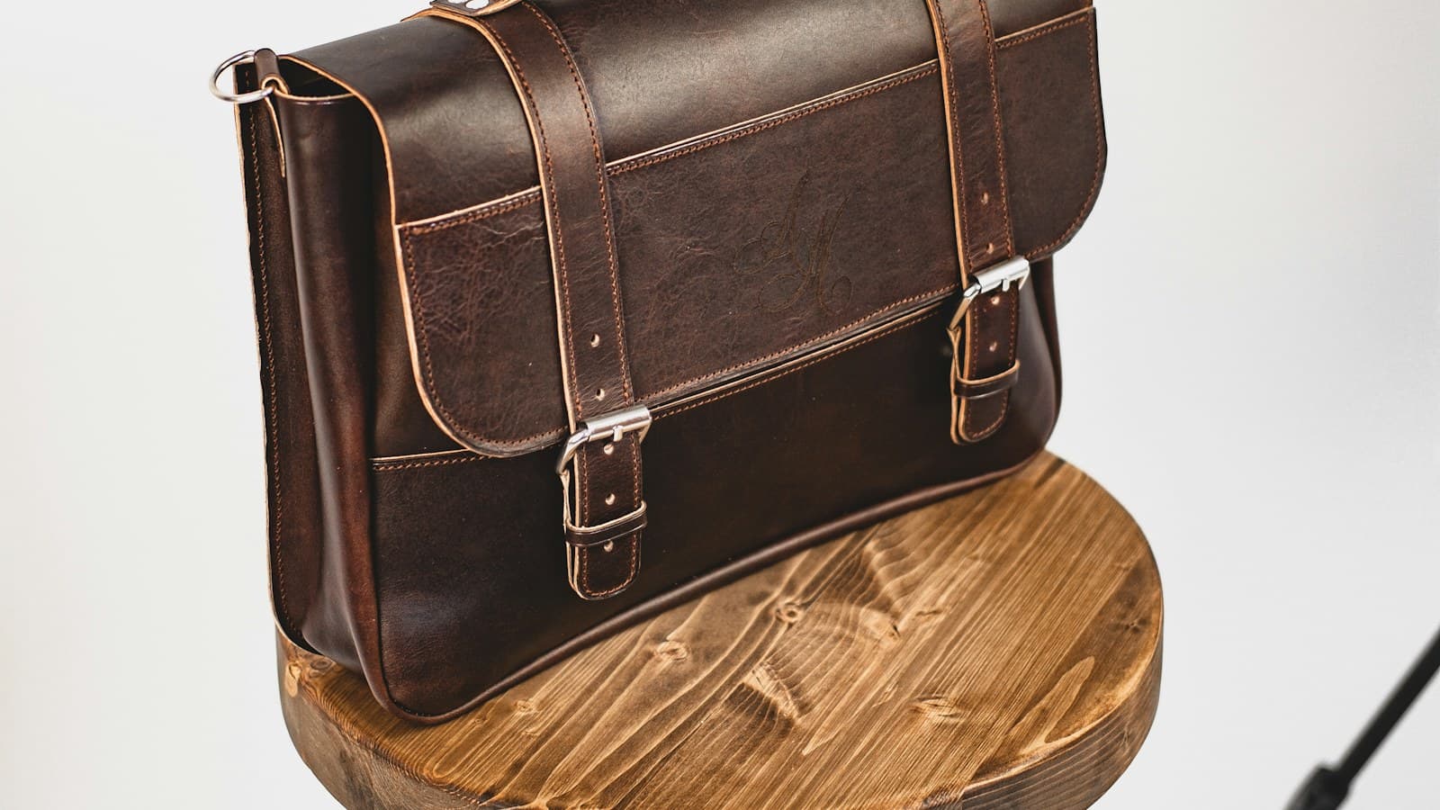 black leather sling bag on brown wooden round table