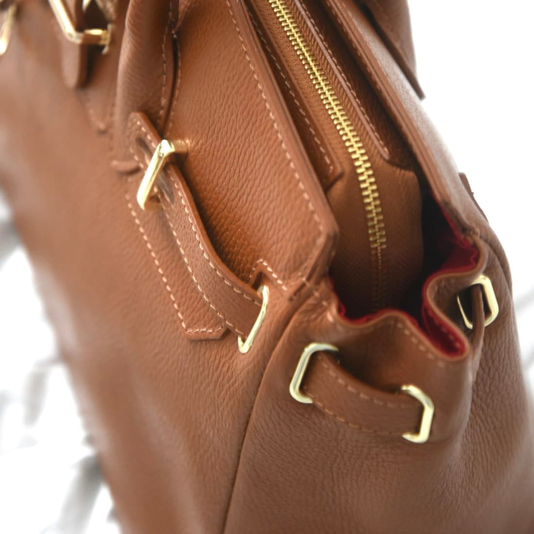 Close-up of a brown leather handbag with gold hardware