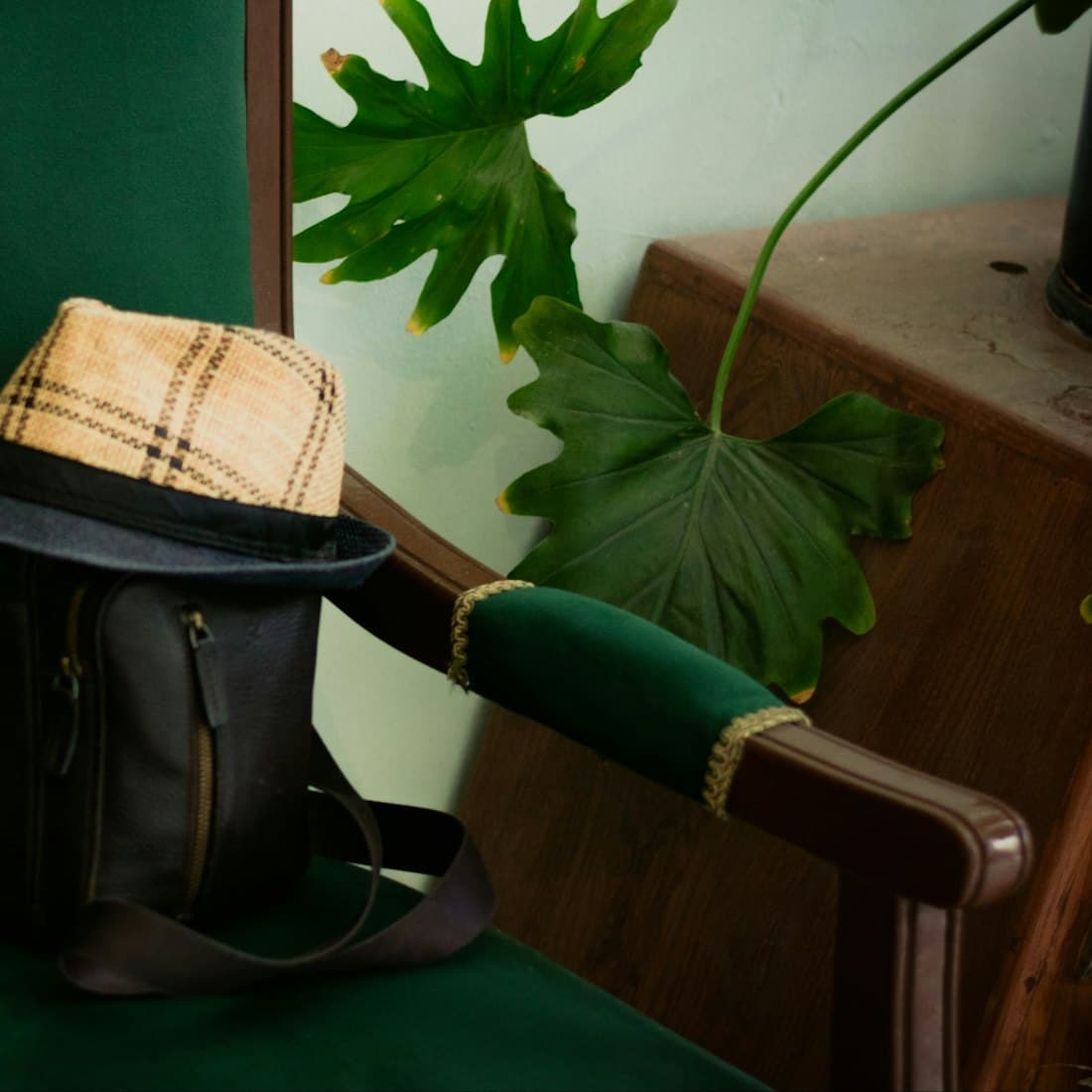 Plaid fedora hat and dark bag on a green chair