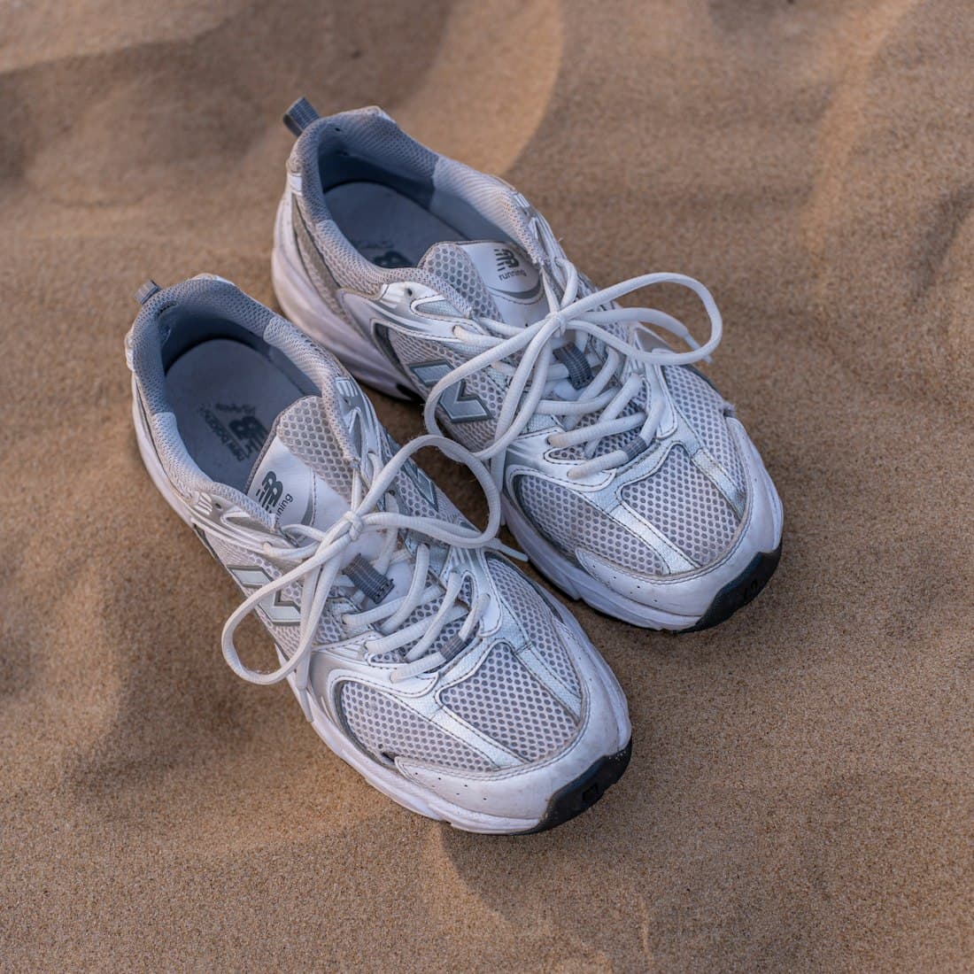 a pair of shoes sitting on top of a sandy beach