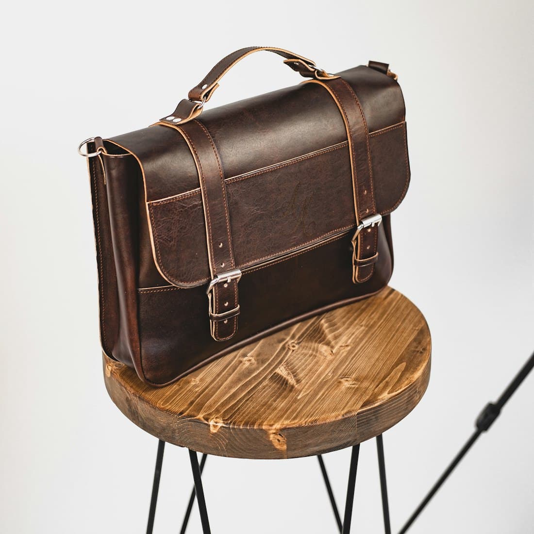 black leather sling bag on brown wooden round table