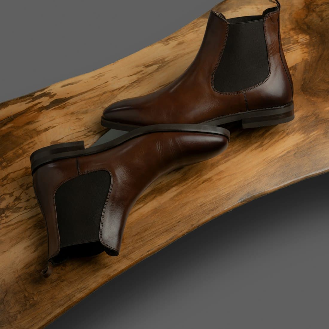 A pair of brown leather chelsea boots on wood