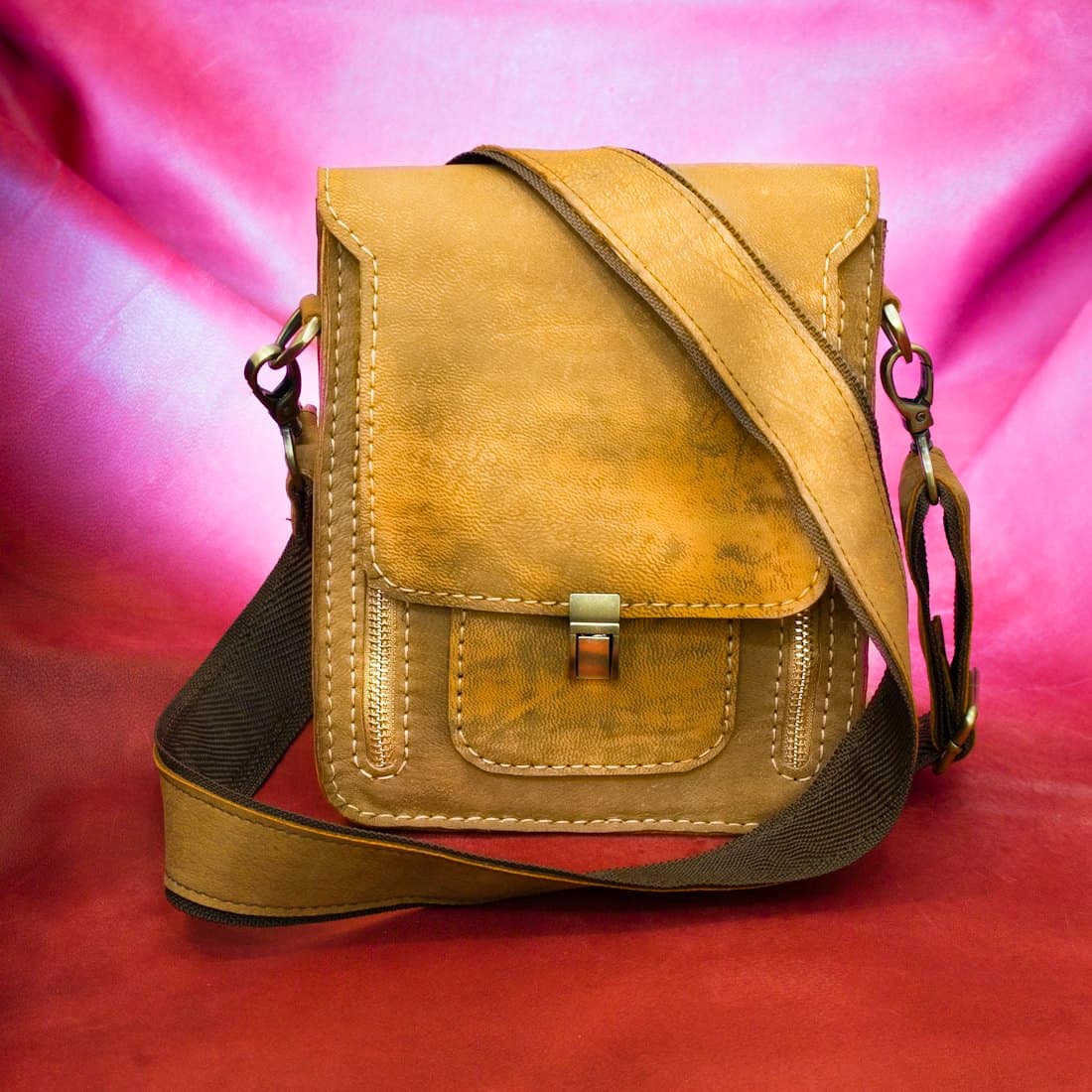 brown leather sling bag on pink textile