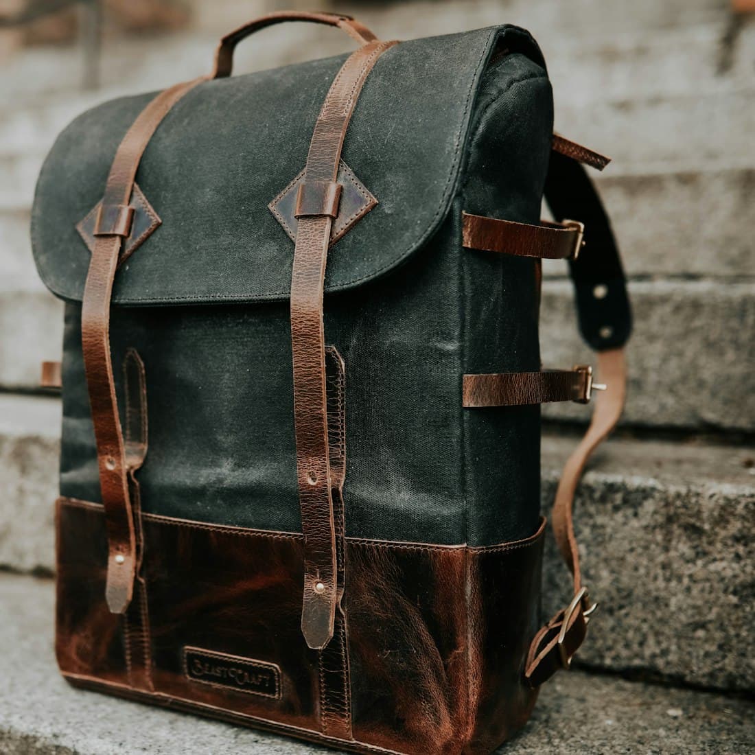 brown and black leather bucket backpack on concrete staircase