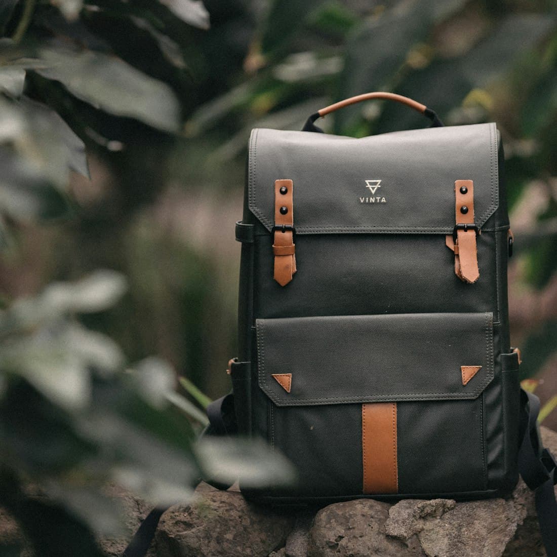 selective focus photography of black and brown leather backpack on rock