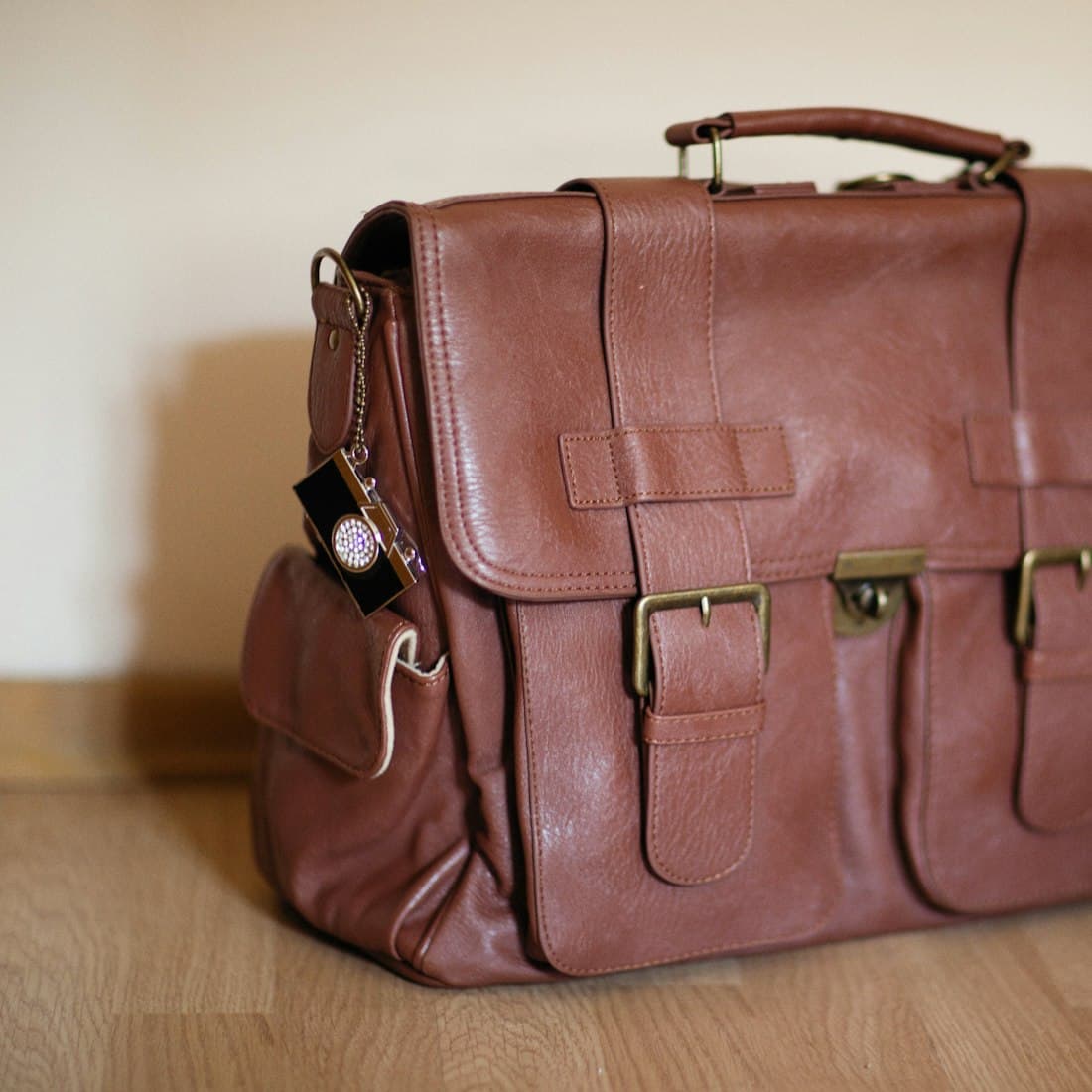 a brown leather briefcase sitting on top of a wooden floor