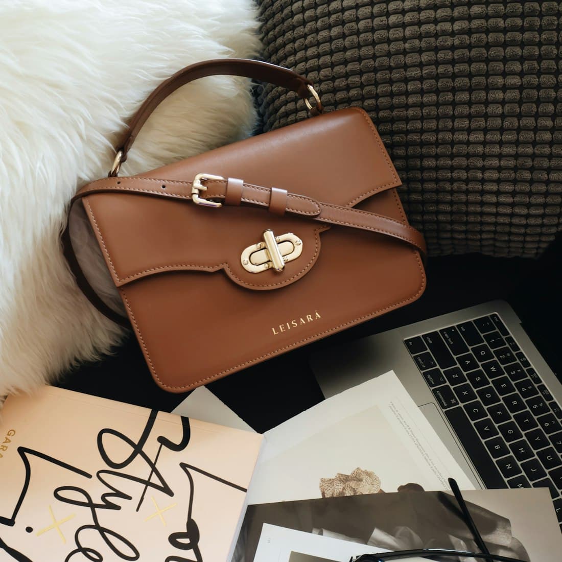 brown leather handbag beside macbook pro