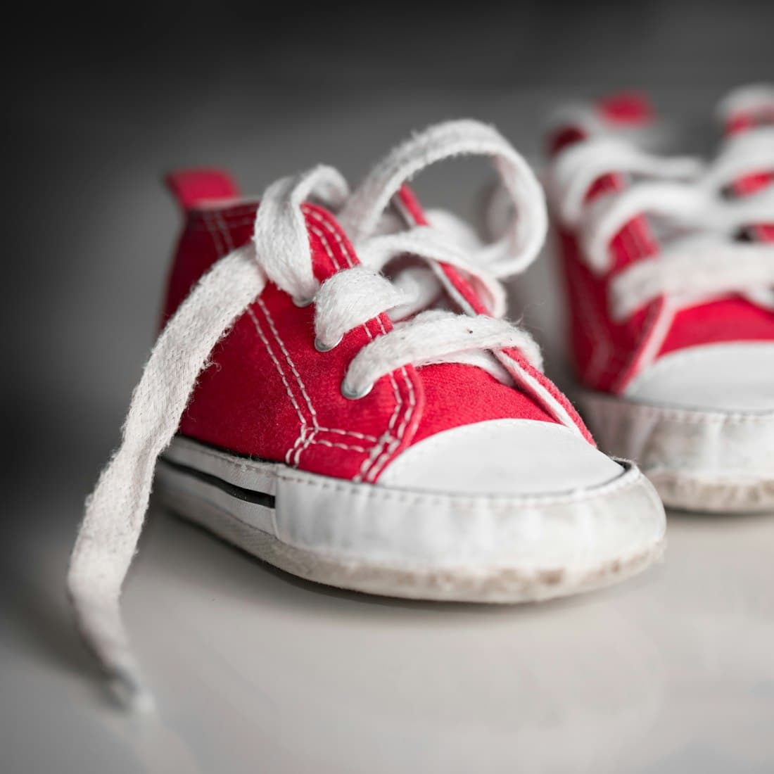 A pair of red baby shoes with white laces