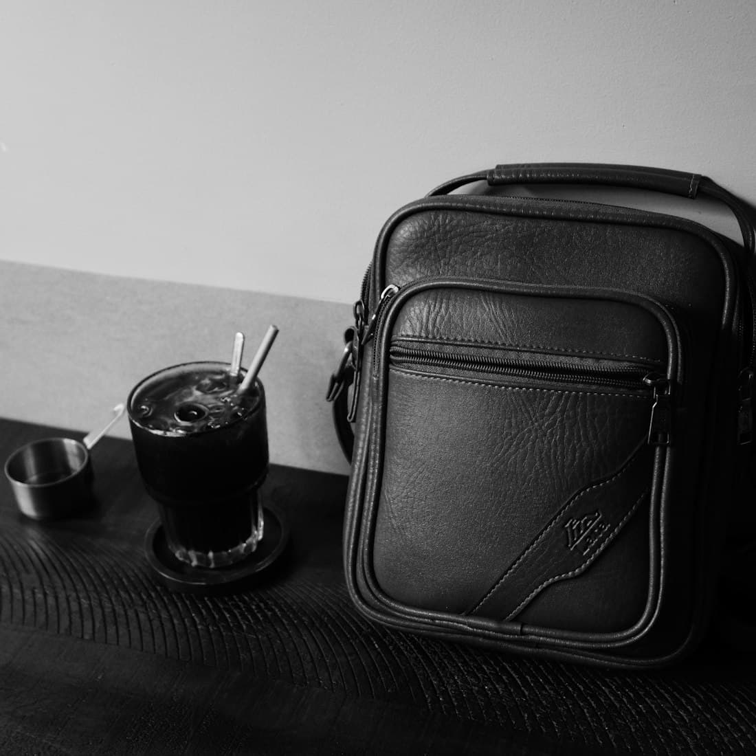 A black leather bag and iced coffee on a table
